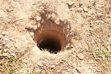 A deep, round hole in the ground for a post when building a fence. Digging holes in the ground for planting a tree seedling. - Powered by Adobe