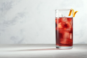 Negroni cocktail in a highball or collins glass with orange peel on a white background. Hero view.