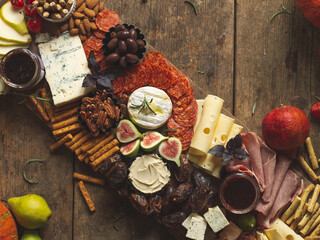 Late fall moody cheese platter with Autumn fruits and snacks on a rustic mountain wooden board with...
