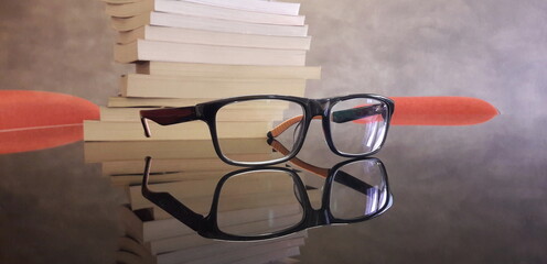 Un paio di occhiali da vista e alcuni libri sulla scrivania di uno studente universitario