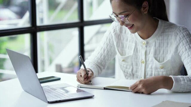 Asian businesswoman working on laptop computer About happy business projects sitting at your desk at home.