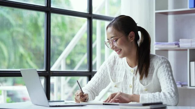 Asian businesswoman working on laptop computer About happy business projects sitting at your desk at home.