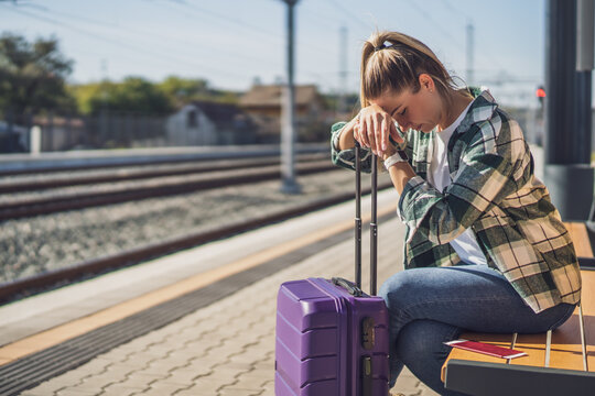Worried woman sitting on a bench at the  train station.
