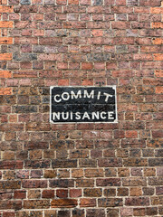 Commit nuisance sign on the red brick wall