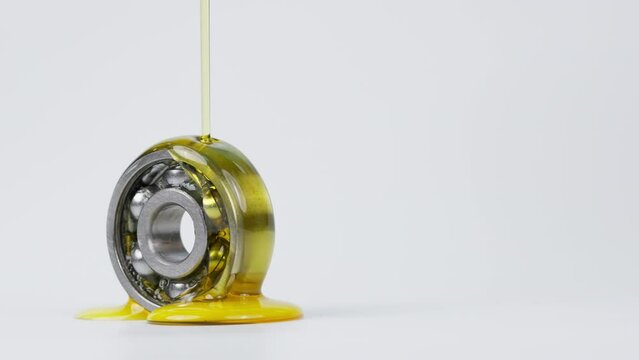 Closed up macro, Pouring automotive engine oil into ball bearing isolated on white background with copy space, engineering and industrial concept. Motor oil on bearing	