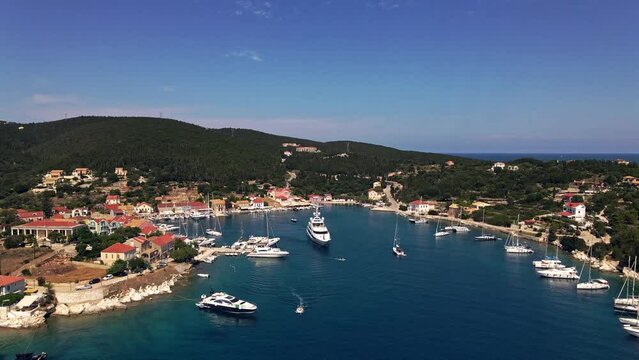 Panoramic aerial video of Fiskardo, Kefalonia island, Greece. Travel sailing boats moored over the turquoise sea