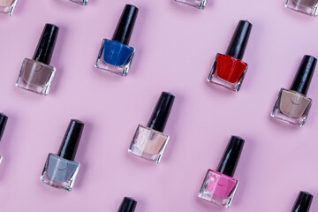 background of rotating bottles or jars varnishes or a coating for manicure or nail polish on a pink background top view, the concept of a beauty salon, cosmetics and care