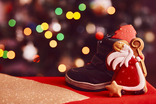  Traditional holiday boots filled with treats and Saint Nicholas cookies on bokeh background. Classical holiday in Europe. Copy space. Festive holidays