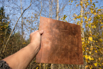 Empty copper plate on the autumn forest background. Nature protection concept. Copy space.