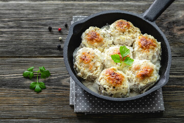 Chicken  meatballs in creamy mushroom sauce in cast iron skillet on wooden background. Top view, copy space, flat lay.