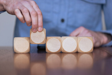 Close up of a business person arranging large wooden blocks. Business strategy and solutions