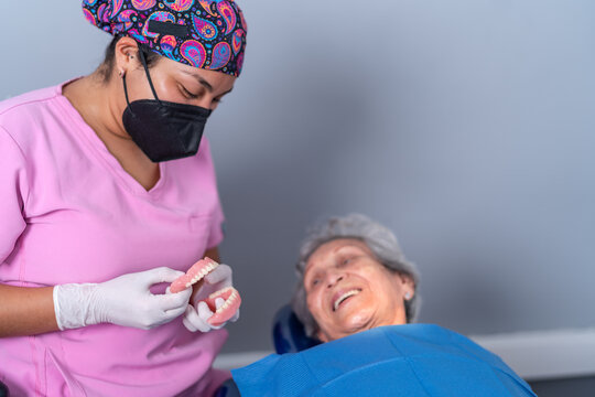 Positive dentist and patient examining denture in clinic