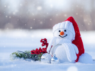 snowman in a red Santa hat in a winter atmosphere outside in the snow.
