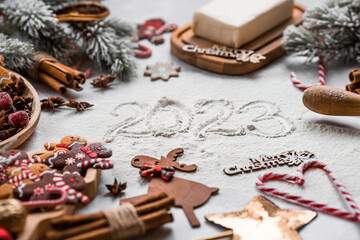 Happy New Year 2023. Banner with kitchen utensils, Christmas decorations, cinnamon, gingerbread and spruce on a marble background. A greeting card for Christmas. The concept of cafes and restaurants.