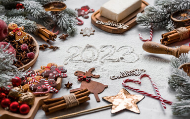 Fototapeta na wymiar Happy New Year 2023. Banner with kitchen utensils, Christmas decorations, cinnamon, gingerbread and spruce on a marble background. A greeting card for Christmas. The concept of cafes and restaurants.