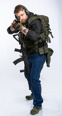 an airsoft player in full gear pointed the muzzle of a pistol at the target. a man in an outfit, in headphones, a bulletproof vest, with a backpack and a belt with additional shells. white background.