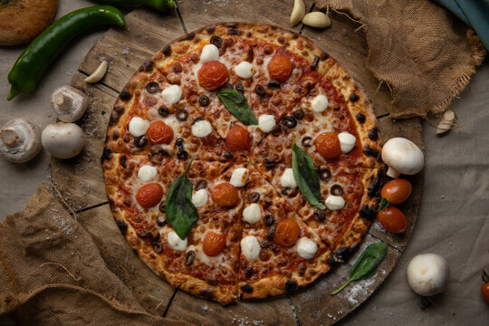 Traditional italian food. Delicious fresh pizza with cheese, tomatoes and onion on wooden background with ingredients, flat lay.
