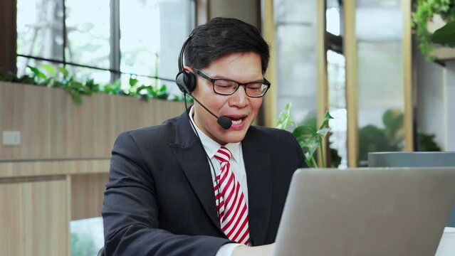 Asian businessman with headphone taking video conference, watching online webinar, virtual training, support custoer from modern corporate office.