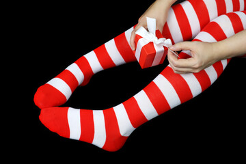 Girl in Christmas knee socks sitting with red gift box on black background. Female outfit for New...