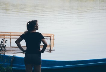 Woman stands in front of boat and fishing net looking away