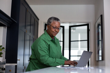 Senior female at home looking at bills and personal finances using a laptop