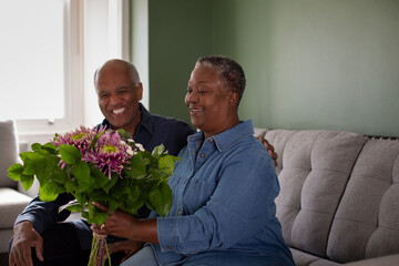Senior African American husband giving bouquet of flowers to wife