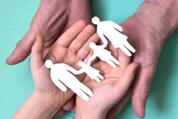 the hands of a man and a child hold a paper-cut silhouette of a family. accident insurance. Family mortgage. housing lottery. family values and relationships