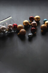 Glass with colorful Christmas baubles on dark background. Selective focus.