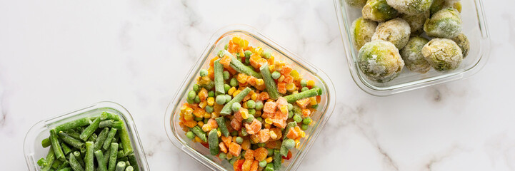 Frozen vegetables in containers banner , frozen cauliflower and asparagus beans, peas and corn, Brussels sprouts and carrots, mix of vegetables, top view, copy space
