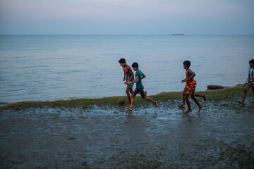 South asian rural teenage boys playing football at a wet ground near a river just before the fifa world cup 