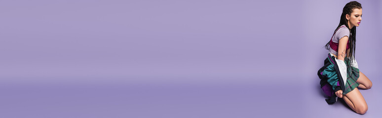 brunette woman with braids and vintage style jacket posing on purple background, banner.