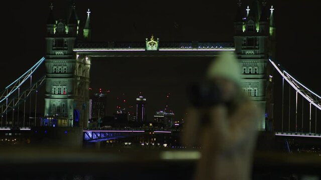 London woman taking pictures near Tower Bridge, at night