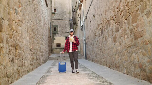 Traveling man with suitcase checking map