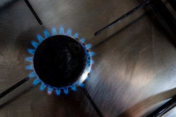 A blue gas flame is seen from the top coming from a household gas burner of a kitchen stove the top...