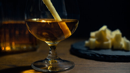 Glass of cane rum with pieces of cane on rustic wooden table and dark background