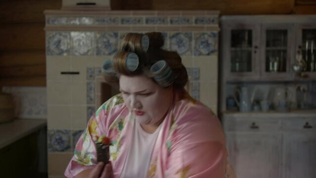 An angry female wearing hair curlers is trying to cook japanese food. An angry lady is cooking the sushi by assembling the ingredients. An Angry Woman is failing in cooking sushi in her home kitchen.