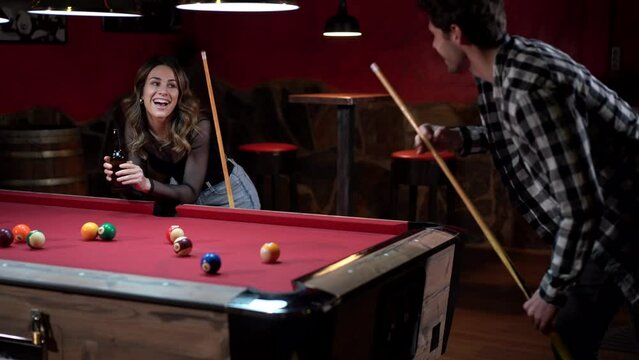 Happy couple playing billiards in pub