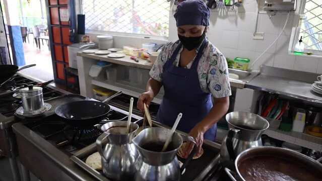 Focused ethnic chef cooking wheat arepas in kitchen