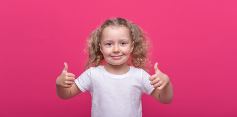 Little cheerful girl on a pink background.
