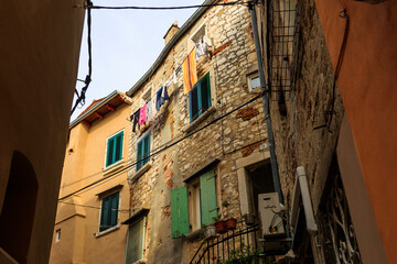 Fototapeta na wymiar Old town alley in the Croatian town of Rovinj with old residential building fronts and freely laid power cables