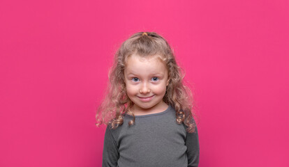 Little nice-looking lovely sweet curious cheerful girl on the pink color background.