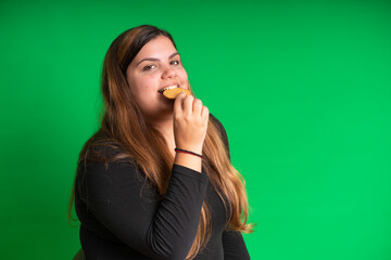 Young woman, wearing black holding a cookie, on  Green Background