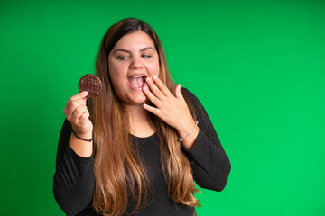 Young woman, wearing black holding a cookie, on  Green Background