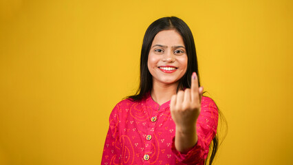 Young Indian girl showing finger after voting, cheerful girl isolated over yellow background - obrazy, fototapety, plakaty