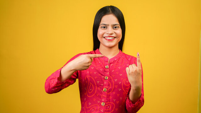 Young Indian girl showing finger after voting, cheerful girl isolated over yellow background