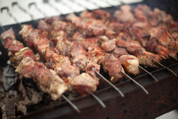 Meat is fried outside. Raw meat planted on blades. Heating food on coals.