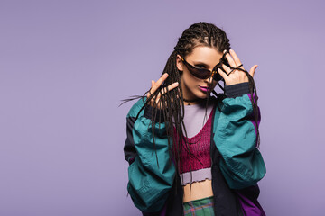 Young woman with braids hairstyle and retro clothes looking at camera isolated on purple.