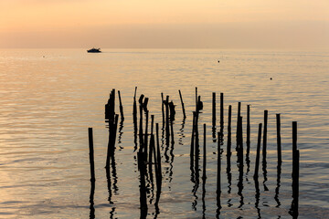 The boat floats on the Black Sea at sunset, in the foreground is a destroyed pier.