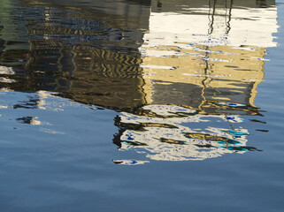 Reflexion and mirroring of a ship in blue water. Abstract distorted boat elements in water. Blue water surface. River ship distorted in the river. Rippled surreal wave background. Abstract texture.	