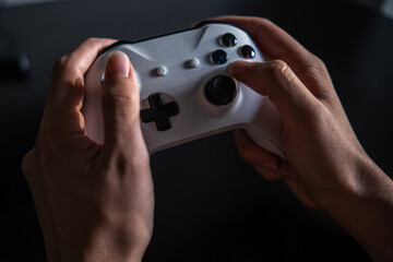 human hand holding console game controller photo in modern black background